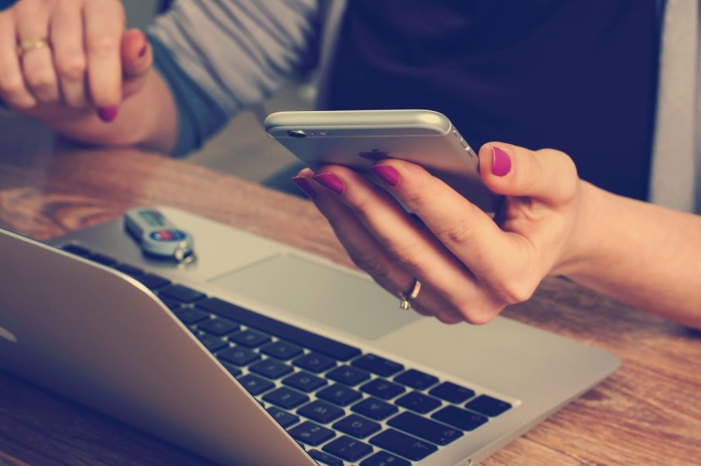 woman holding phone while working on pc