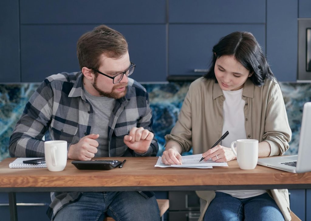 Funding Freedom: 6 Essential Strategies To Escape The Clutches Of Debt 1 Man and Woman Sitting at Table with Documents